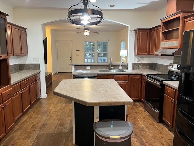 kitchen with stainless steel range with electric cooktop, a kitchen island, hardwood / wood-style flooring, and sink