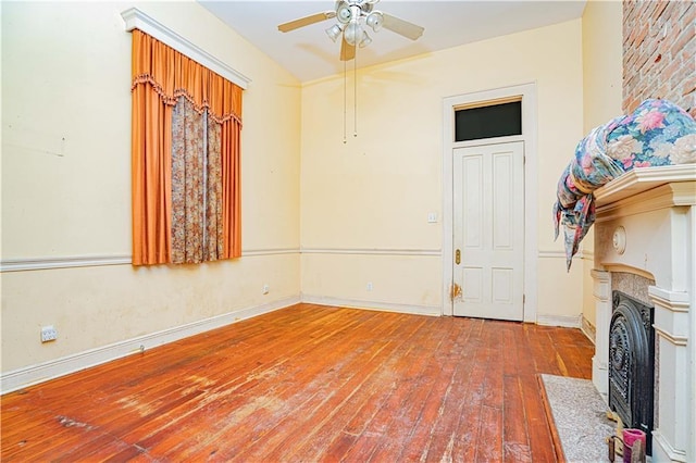 interior space with ceiling fan, a fireplace, and hardwood / wood-style floors