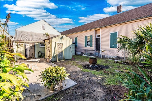 rear view of property with a patio area and a storage unit