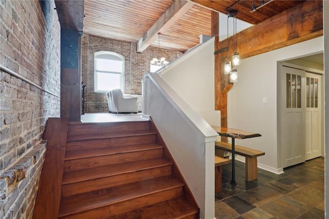 stairs with beam ceiling, brick wall, and wooden ceiling