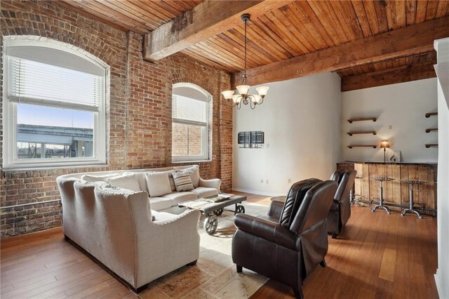 living room featuring a notable chandelier, light hardwood / wood-style floors, beamed ceiling, brick wall, and wooden ceiling