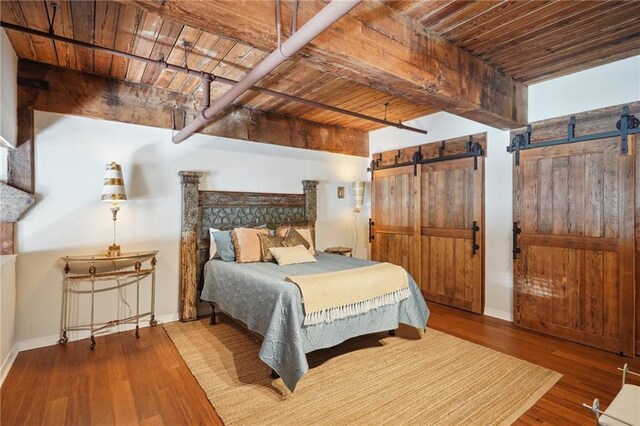 bedroom with hardwood / wood-style flooring, wood ceiling, beamed ceiling, and a barn door