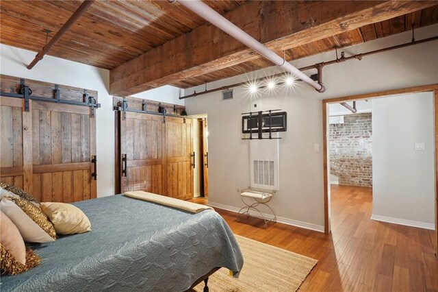 bedroom featuring brick wall, hardwood / wood-style floors, beamed ceiling, wooden ceiling, and a barn door