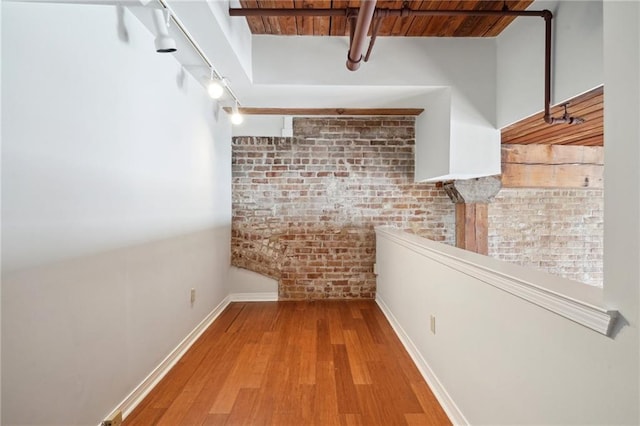 hallway with brick wall, wood ceiling, and light wood-type flooring