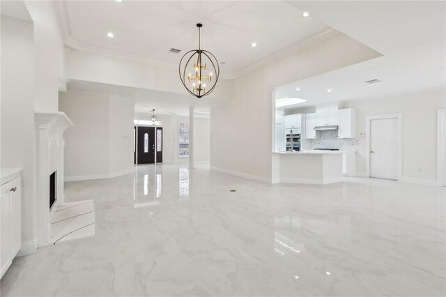 unfurnished living room featuring crown molding and a chandelier