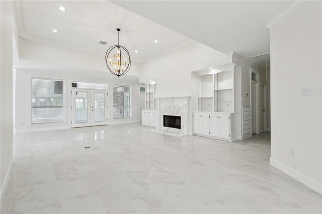 unfurnished living room with a premium fireplace, a notable chandelier, and crown molding