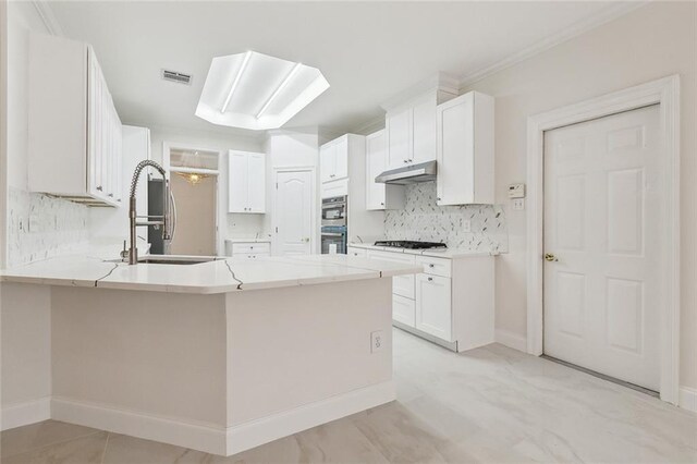 kitchen featuring gas stovetop, kitchen peninsula, sink, white cabinets, and tasteful backsplash