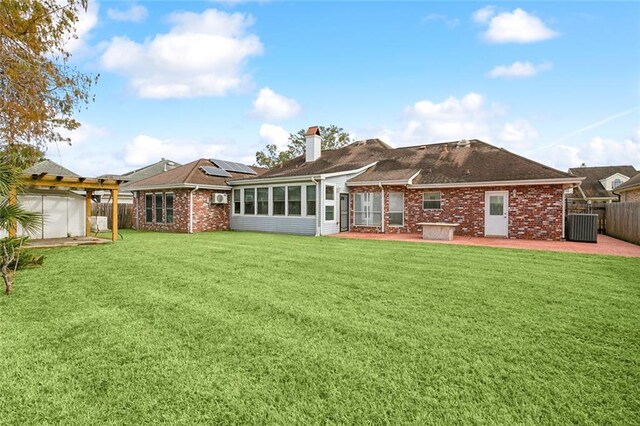 back of property with solar panels, a patio, a lawn, and a sunroom