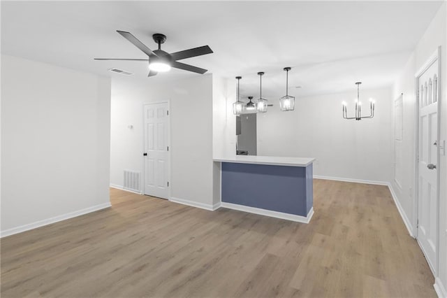 interior space with ceiling fan with notable chandelier and light hardwood / wood-style flooring