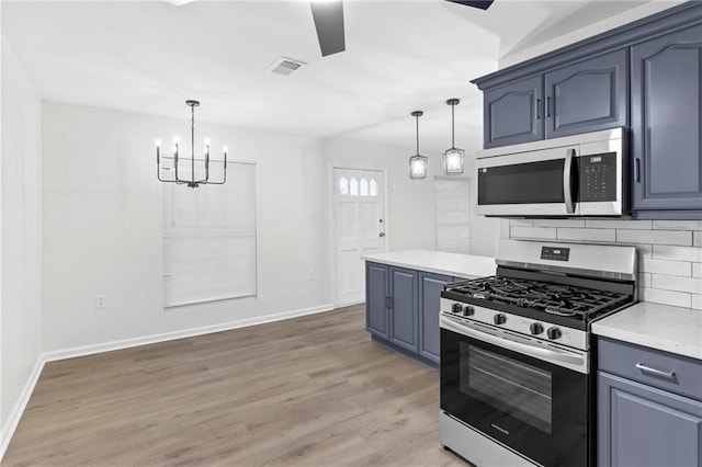 kitchen with tasteful backsplash, appliances with stainless steel finishes, decorative light fixtures, and hardwood / wood-style floors