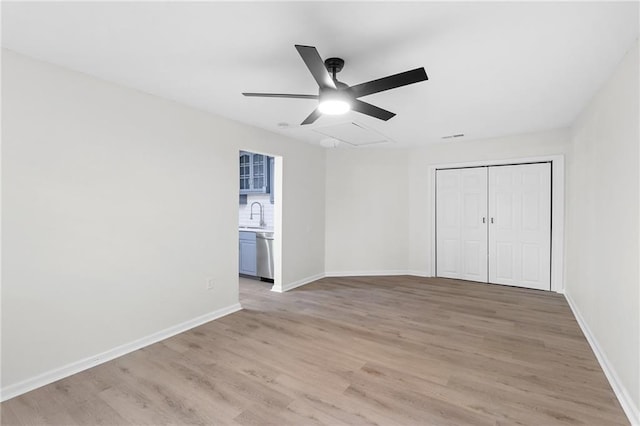 unfurnished bedroom featuring a closet, sink, ceiling fan, and light hardwood / wood-style flooring