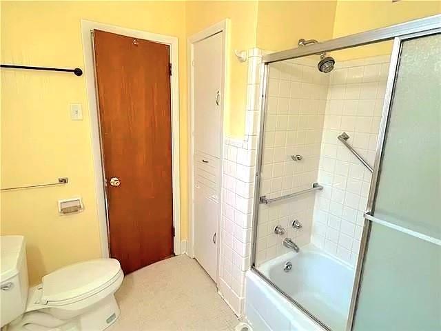 bathroom featuring shower / bath combination with glass door and toilet