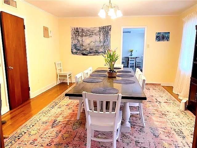 dining area featuring hardwood / wood-style floors, a notable chandelier, and ornamental molding