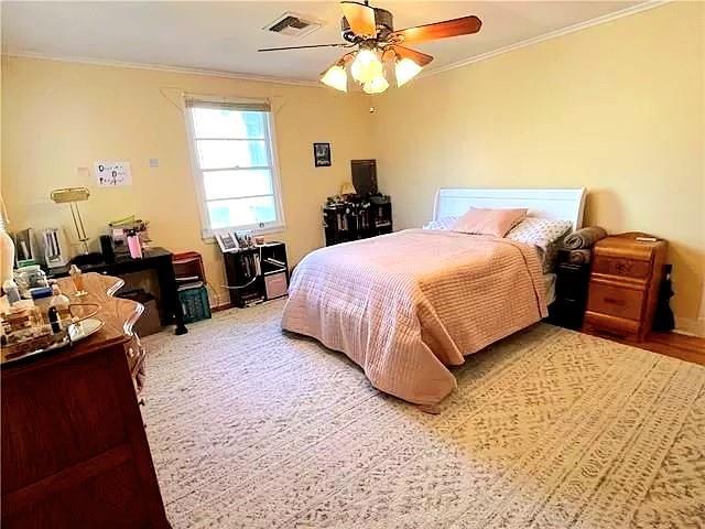 bedroom with ceiling fan and crown molding