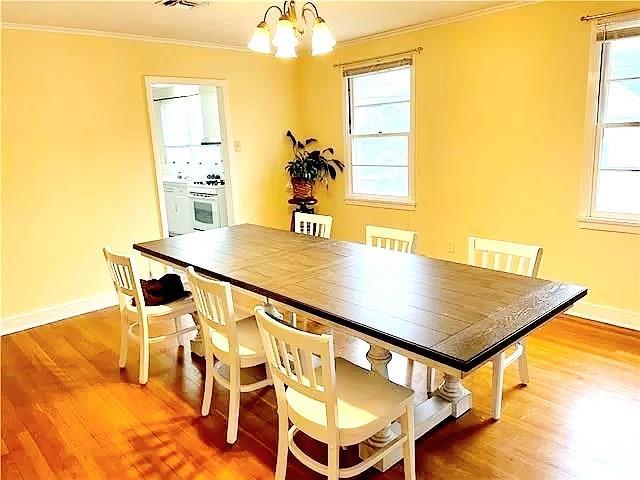 dining room featuring hardwood / wood-style flooring, a chandelier, crown molding, and plenty of natural light