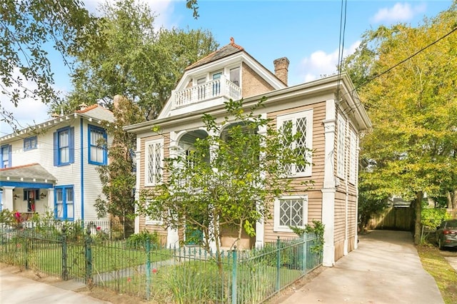 7917 Sycamore St, New Orleans, LA 70118 - view of front of property featuring a balcony, a chimney, a fenced front yard, and driveway