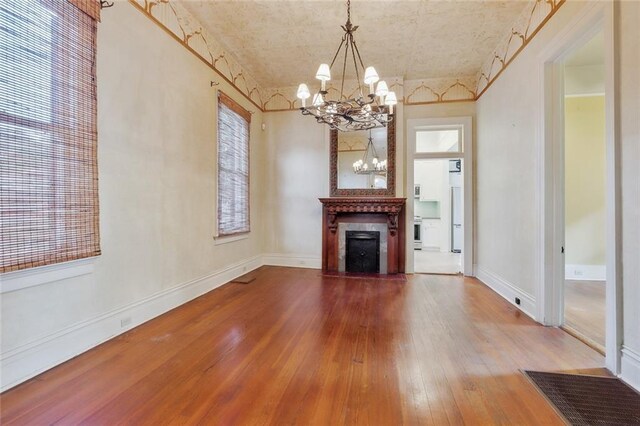 unfurnished living room with hardwood / wood-style floors, an inviting chandelier, and a large fireplace