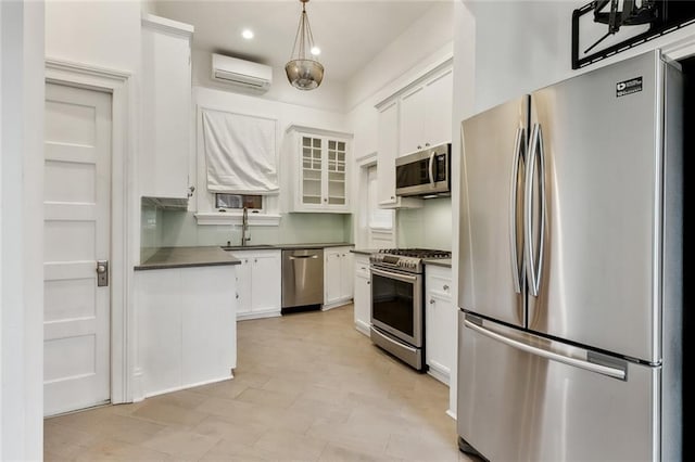 kitchen with stainless steel appliances, sink, decorative light fixtures, white cabinetry, and a wall mounted air conditioner