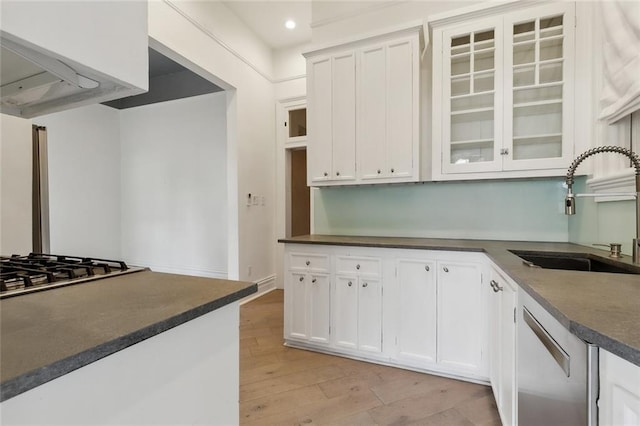 kitchen featuring range hood, stainless steel appliances, light hardwood / wood-style floors, white cabinetry, and sink