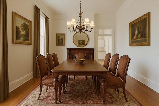 7917 Sycamore St, New Orleans, LA 70118 - dining space with a chandelier, baseboards, wood finished floors, and crown molding
