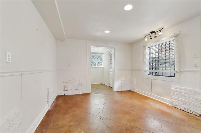 tiled empty room featuring rail lighting