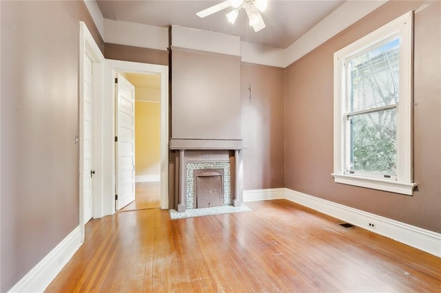 7917 Sycamore St, New Orleans, LA 70118 - unfurnished living room featuring wood finished floors, ceiling fan, baseboards, and a fireplace with flush hearth