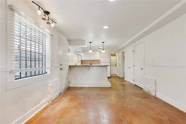 kitchen with kitchen peninsula, white refrigerator, a kitchen bar, decorative light fixtures, and backsplash