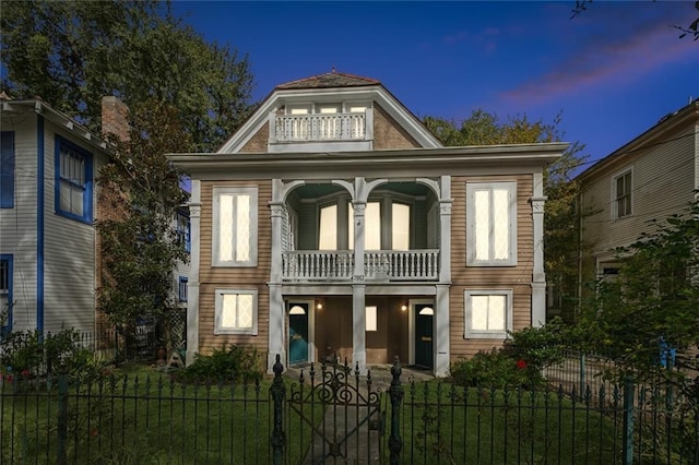 view of front of house with a balcony and a yard