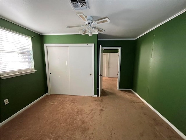 unfurnished bedroom with crown molding, ceiling fan, carpet, and a closet