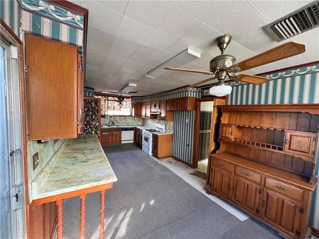 kitchen featuring tasteful backsplash, sink, dishwashing machine, ceiling fan, and white gas stove