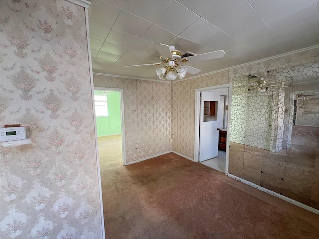 spare room with crown molding, ceiling fan, and carpet flooring