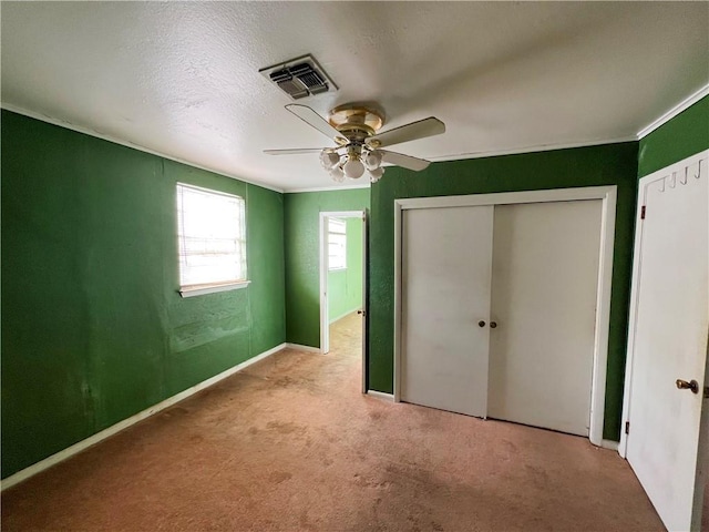 unfurnished bedroom featuring light carpet, crown molding, a closet, and ceiling fan