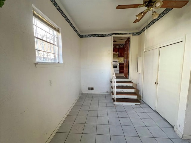 basement featuring ceiling fan and light tile patterned floors