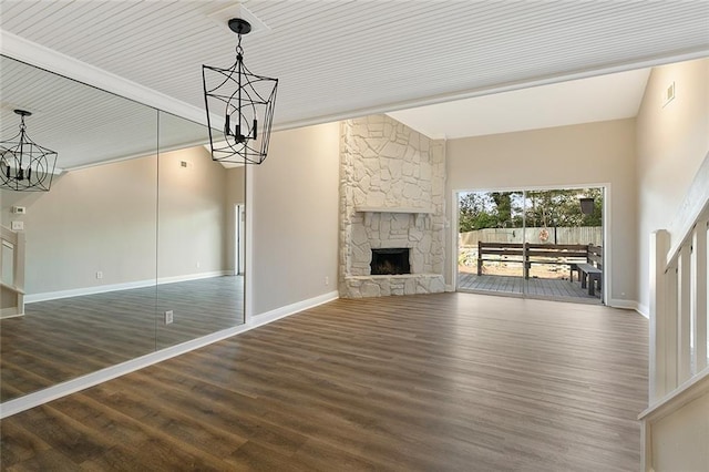 unfurnished living room featuring an inviting chandelier, dark hardwood / wood-style flooring, vaulted ceiling with beams, and a stone fireplace