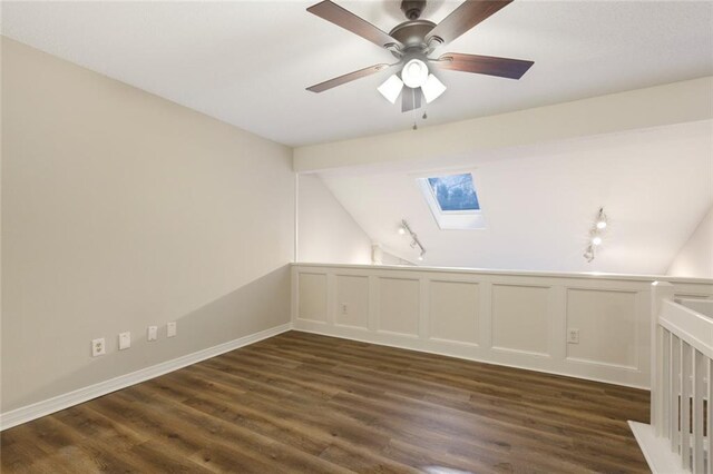 empty room with dark hardwood / wood-style floors, lofted ceiling with skylight, and ceiling fan