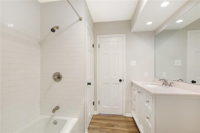 bathroom featuring tiled shower / bath combo, hardwood / wood-style floors, and vanity