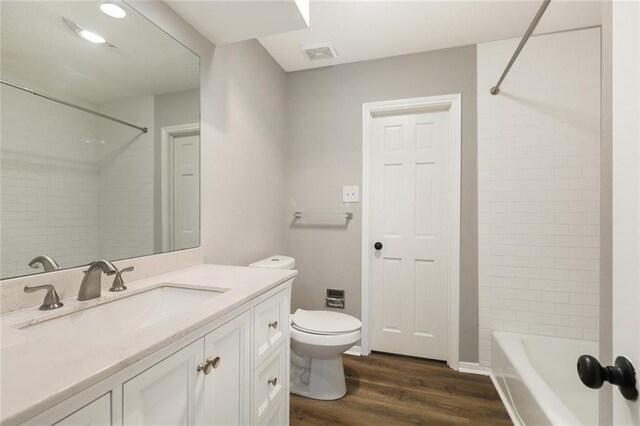 full bathroom featuring toilet, tiled shower / bath combo, hardwood / wood-style flooring, and vanity