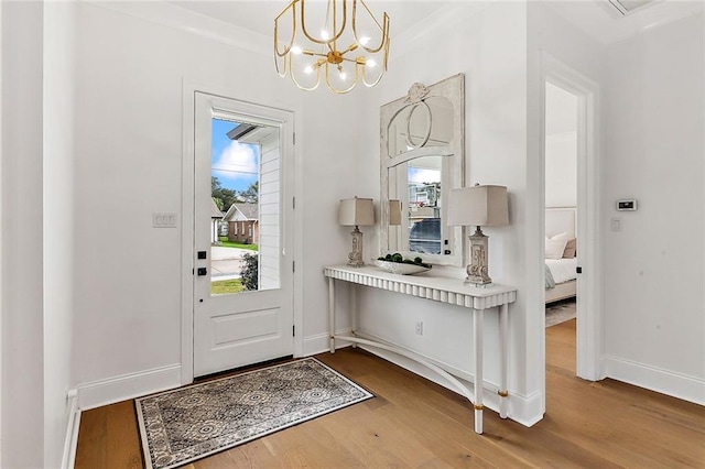 foyer entrance featuring hardwood / wood-style flooring, an inviting chandelier, ornamental molding, and plenty of natural light