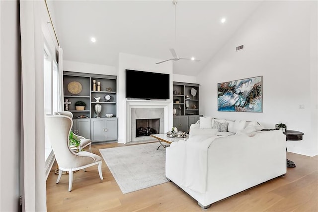 living room featuring light wood-type flooring, visible vents, recessed lighting, and a fireplace