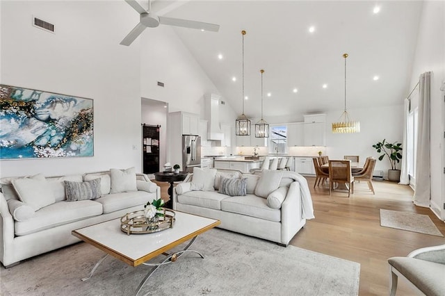 living room featuring light wood-type flooring, visible vents, high vaulted ceiling, ceiling fan with notable chandelier, and recessed lighting