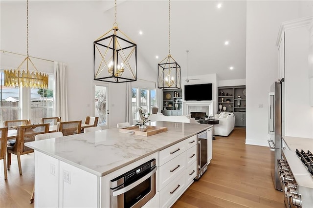 kitchen with white cabinets, light wood-type flooring, high end fridge, and a chandelier