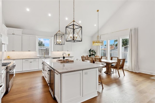 1012 Athania Pkwy, Metairie, LA 70001 - kitchen with stainless steel stove, a center island, a chandelier, high vaulted ceiling, and healthy amount of natural light