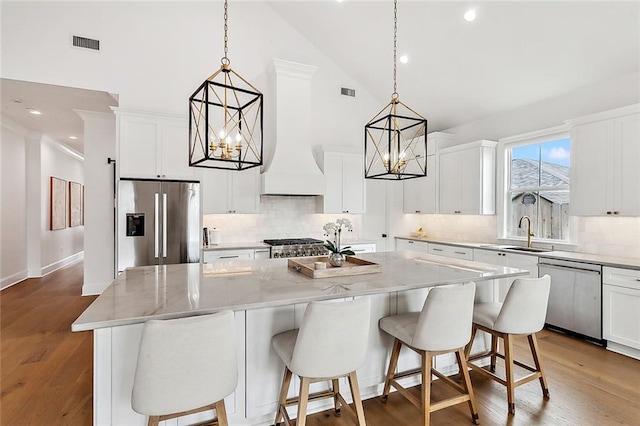 1012 Athania Pkwy, Metairie, LA 70001 - kitchen featuring appliances with stainless steel finishes, a sink, a chandelier, high vaulted ceiling, and a center island