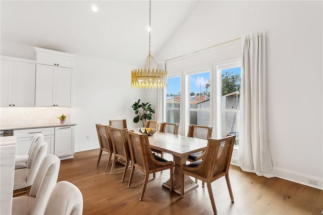 dining area featuring baseboards, a notable chandelier, wood finished floors, and high vaulted ceiling