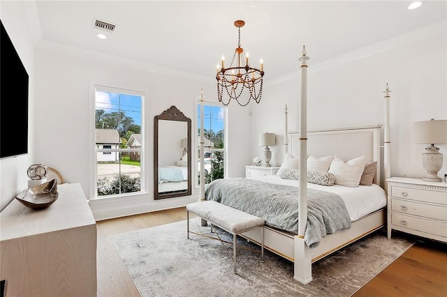 bedroom with wood finished floors, visible vents, an inviting chandelier, recessed lighting, and crown molding