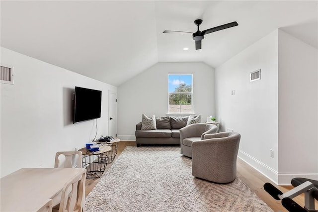 living room featuring visible vents, wood finished floors, baseboards, and vaulted ceiling