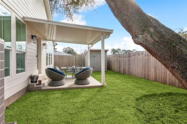 view of yard featuring an outdoor structure, a storage unit, a fenced backyard, and a patio