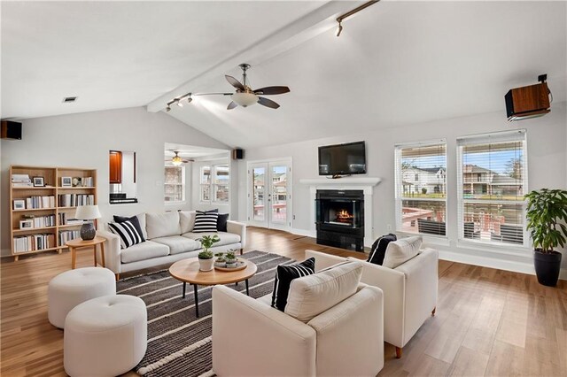 living room featuring light hardwood / wood-style flooring, track lighting, french doors, and vaulted ceiling with beams