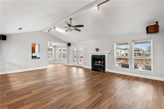 unfurnished living room with rail lighting, ceiling fan, french doors, light hardwood / wood-style flooring, and lofted ceiling with beams