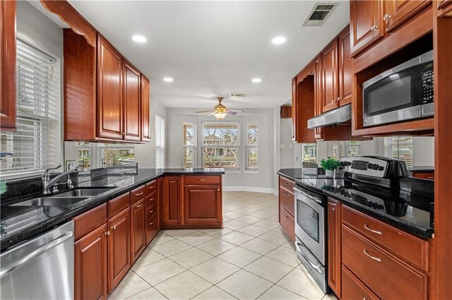 kitchen featuring kitchen peninsula, ceiling fan, stainless steel appliances, dark stone counters, and sink